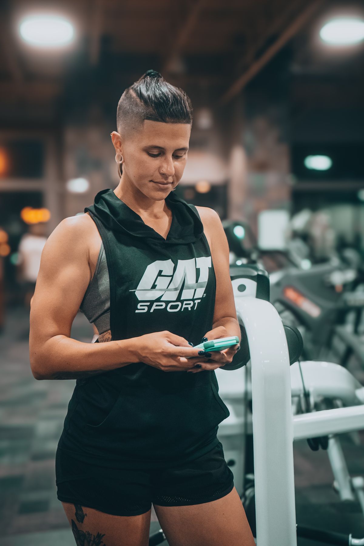 A member checking her phone between sets in a modern gym