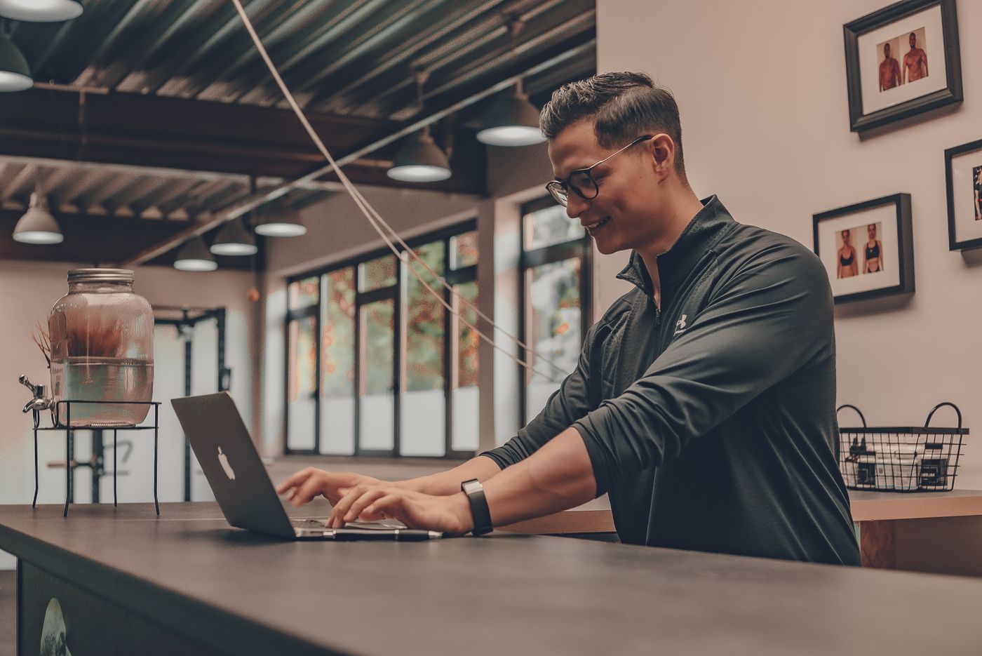 A gym manager working on a laptop at the front desk